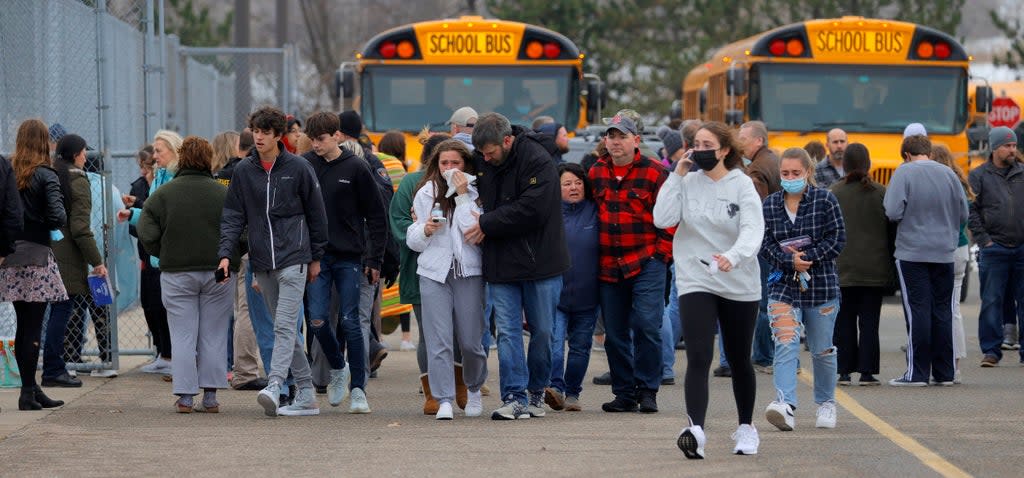 Parents walk away with their kids from the Meijer’s parking lot, where many students gathered following an active shooter situation at Oxford High School, Tuesday, Nov. 30, 2021, in Oxford, Michigan. Police took a suspected shooter into custody and there were multiple victims, the Oakland County Sheriff’s office said (AP)