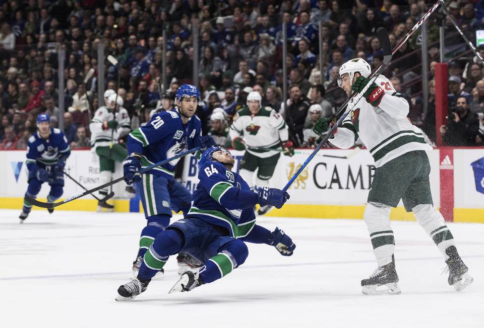 Minnesota Wild's Carson Soucy, right, checks Vancouver Canucks' Tyler Motte during the second period of an NHL hockey game Wednesday, Feb. 19, 2020, in Vancouver, British Columbia. (Darryl Dyck/The Canadian Press via AP)