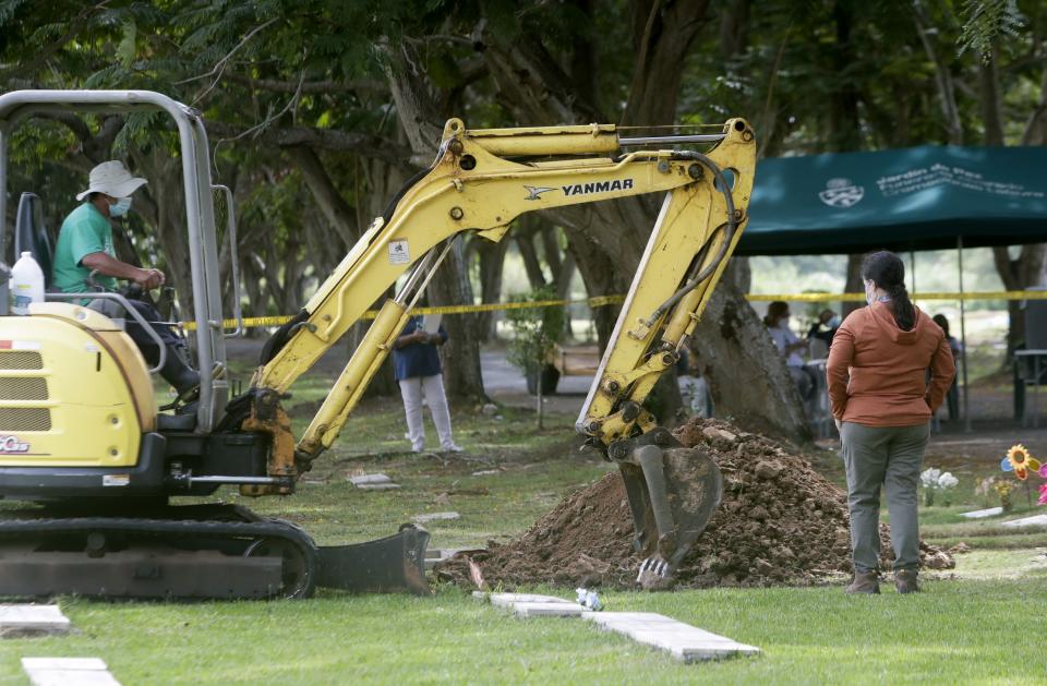 Trabajadores forenses exhuman lo que se cree que son los restos del teniente Braulio Bethancourt, víctima de la invasión estadounidense de 1989, en el cementerio Jardín de Paz en la ciudad de Panamá, el jueves 15 de abril de 2021. (AP Foto/Arnulfo Franco)