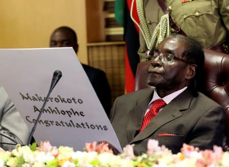 FILE PHOTO: Zimbabwe's President Robert Mugabe reads a card during his 93rd birthday celebrations in Harare