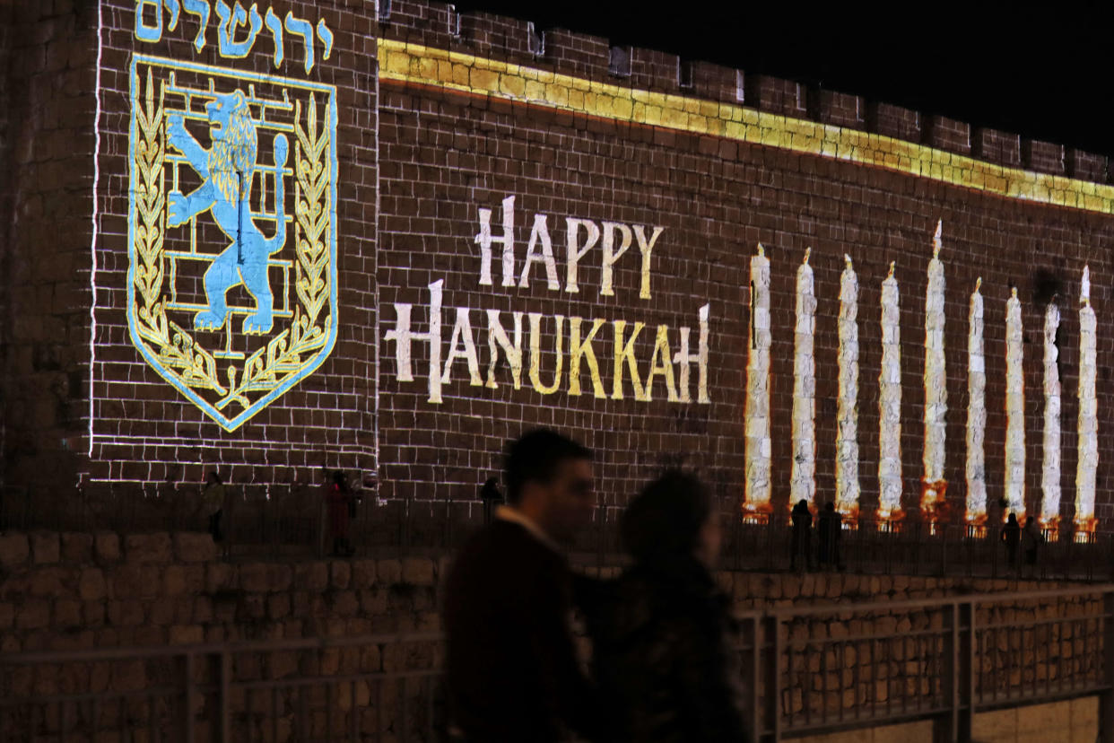 A projection of lit candles is displayed on the old city walls of Jerusalem marking the Jewish holiday of Hanukkah, on November 28, 2021. (Photo by Ahmad GHARABLI / AFP)