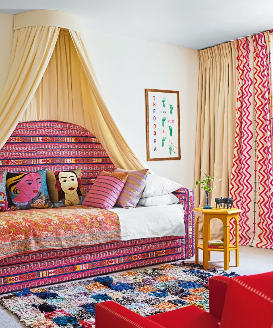 Colorful kids bedroom with canopy bed, pink and cream curtains, yellow side table, patterned rug