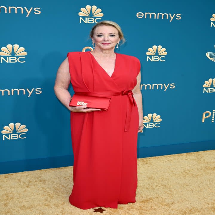 J Smith-Cameron in a red dress holding a purse