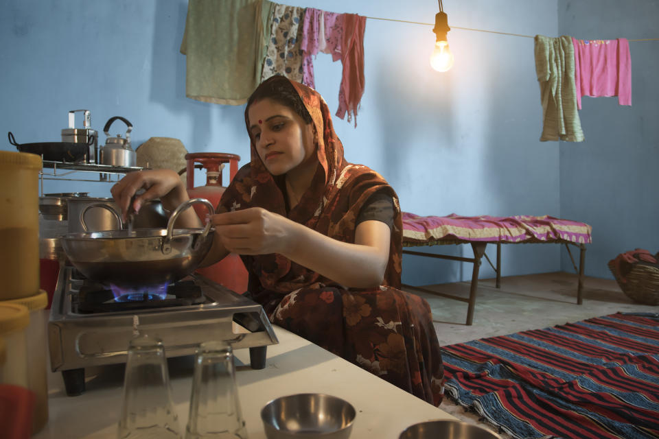Indian Woman Sitting In Kitchen Cooking Food