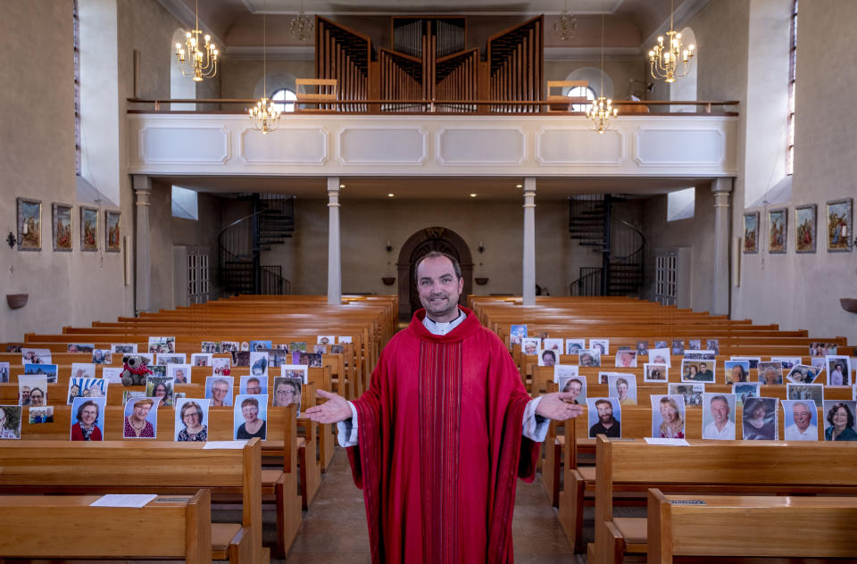 FILE - In this April 4, 2020 file photo, Priest Christian Rauch stands in front of photos with parishioners in the catholic St. Andreas church in Lampertheim, Germany. Due to the coronavirus no services are held these days. More than 50,000 people have died after contracting COVID-19 in Germany, a number that has risen swiftly over recent weeks as the country has struggled to bring down infection figures. (AP Photo/Michael Probst, File)