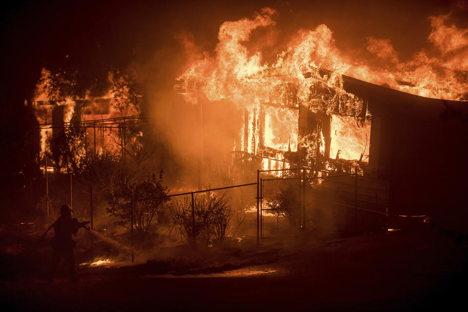 <p>A firefighter sprays water as flames from a wildfire consume a residence near Oroville, Calif., on Sunday, July 9, 2017. Evening winds drove the fire through several neighborhoods leveling homes in its path. (AP Photo/Noah Berger) </p>