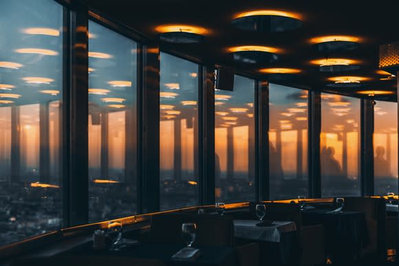 Several tables lining the windows of a restaurant overlooking a city.