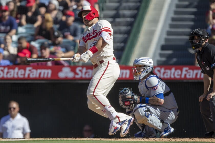 Los Angeles Angels designated hitter Mike Trout, left, hits a run-scoring single to score Brandon Marsh.