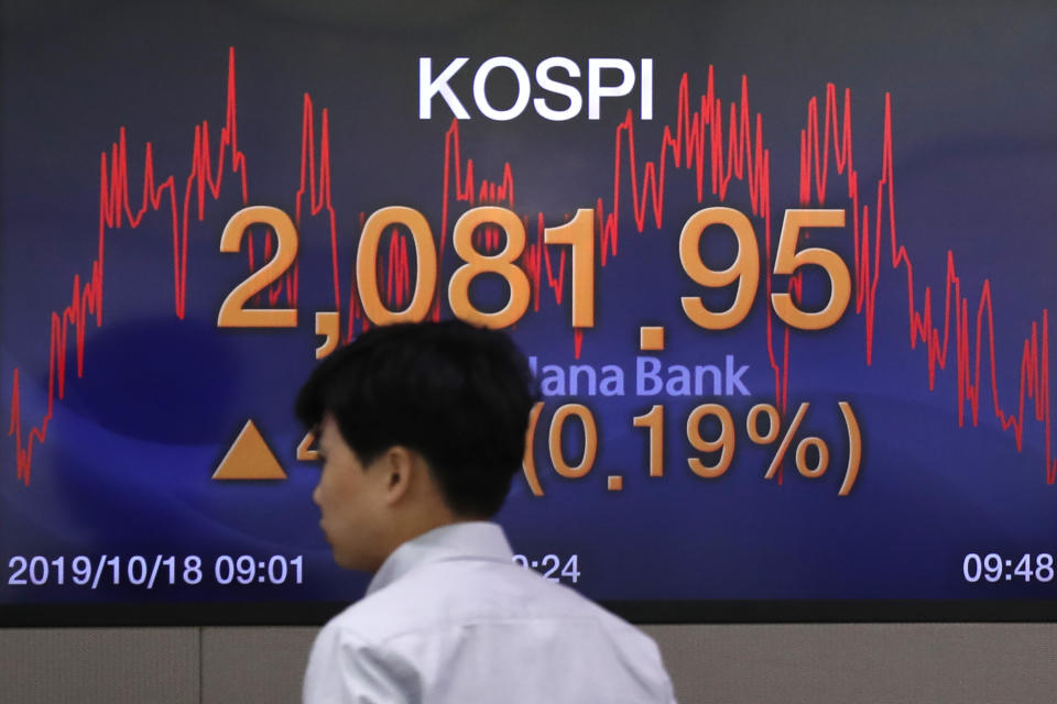 A currency trader walks by a screen showing the Korea Composite Stock Price Index (KOSPI) at the foreign exchange dealing room in Seoul, South Korea, Friday, Oct. 18, 2019. Share prices retreated in Asia after China reported Friday that its economy grew at an annual rate of 6.0% in the latest quarter. (AP Photo/Lee Jin-man)