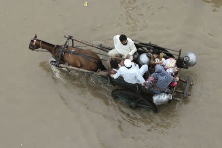 A Pakistani family travels on a horse-cart through flood road following heavy rain in Lahore September 4, 2014. REUTERS/Mohsin Raza