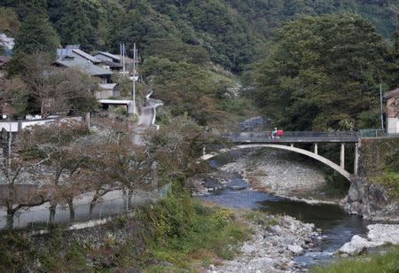 A postman riding a motorbike drives past on a bridge in Nanmoku Village, northwest of Tokyo, Japan October 12, 2017. Picture taken October 12, 2017. REUTERS/Issei Kato