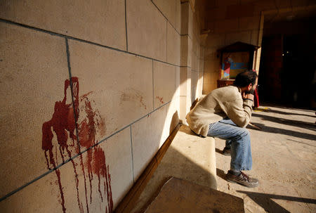 An Egyptian Christian sits on a bench near a blood stain on a wall at the scene following a bombing inside Cairo's Coptic cathedral in Egypt December 11, 2016. REUTERS/Amr Abdallah Dalsh