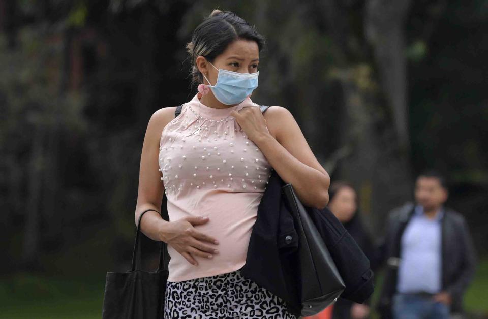 A pregnant woman wears a face mask as a preventive measure against the spread of the new coronavirus, COVID-19, as she waits for the bus in Bogota, on March 16, 2020. - The Colombian government announced the indefinite suspension of face-to-face classes in public schools and universities as a preventive measure against the COVID-19 pandemic. (Photo by Raul ARBOLEDA / AFP) (Photo by RAUL ARBOLEDA/AFP via Getty Images)