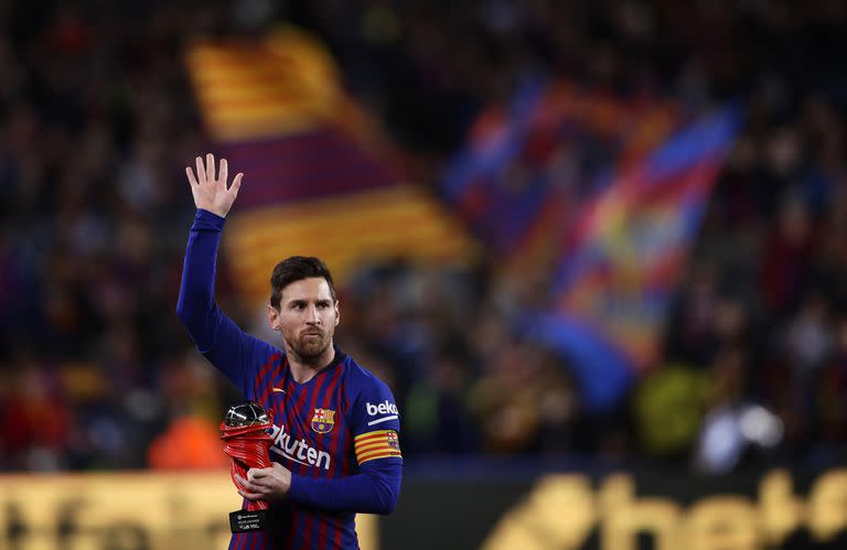 En esta fotografía del sábado 6 de abril de 2019, el delantero del Barcelona Lionel Messi saluda a la multitud mientras sostiene el trofeo al mejor jugador de La Liga española antes de un partido de fútbol entre el FC Barcelona y el Atlético de Madrid en el estadio Camp Nou de Barcelon, España