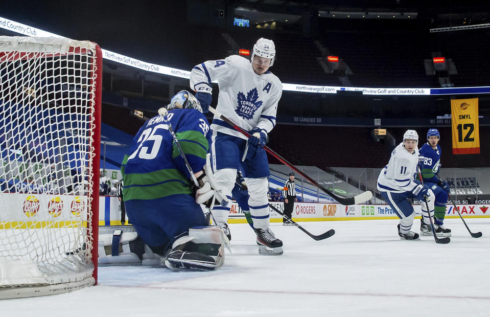 Vancouver Canucks goalie Thatcher Demko, left, makes the save while being screened by Toronto Maple Leafs' Auston Matthews (34) during the second period of an NHL hockey game in Vancouver, British Columbia, on Saturday, March 6, 2021. (Darryl Dyck/The Canadian Press via AP)