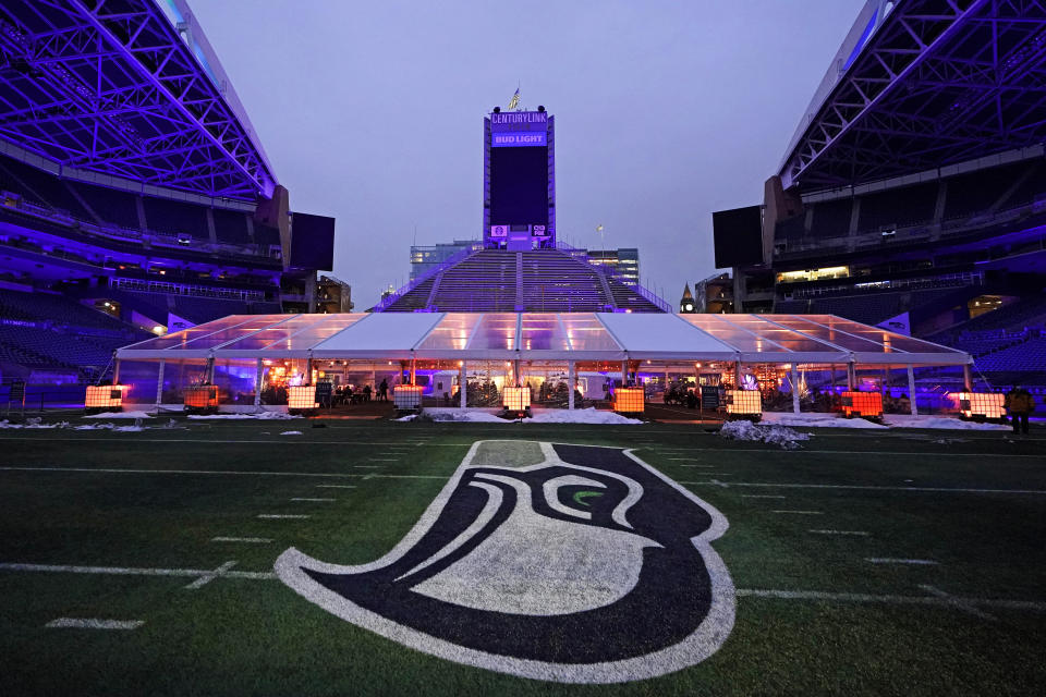 People eat dinner in an outdoor dining tent set up near the logo of the Seattle Seahawks NFL football team on the 50-yard line at Lumen Field, Thursday, Feb. 18, 2021, in Seattle. The "Field To Table" event was the first night of several weeks of dates that offer four-course meals cooked by local chefs and served on the field at tables socially distanced as a precaution against the COVID-19 pandemic, which has severely limited options for dining out at restaurants in the area. (AP Photo/Ted S. Warren)