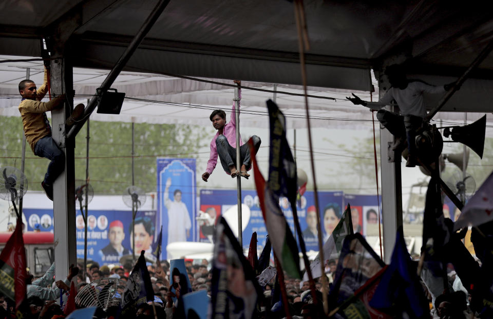 Youth climb on poles for a vantage view as supporters of Bahujan Samaj Party (BSP), Samajwadi Party (SP) and Rashtriya Lok Dal (RLD) gather during an election rally in Deoband, Uttar Pradesh, India, Sunday, April 7, 2019. Political archrivals in India's most populous state rallied together Sunday, asking voters to support a new alliance created with the express purpose of defeating Prime Minister Narendra Modi's ruling Hindu nationalist Bharatiya Janata Party. (AP Photo/Altaf Qadri)