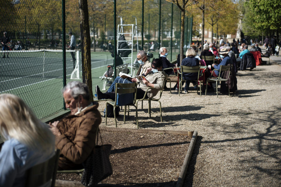 People, some wearing face masks to prevent the spread of the coronavirus, enjoy the sun in an outdoor seating area in Luxembourg gardens, in Paris, Monday, April 19, 2021.(AP Photo/Lewis Joly)