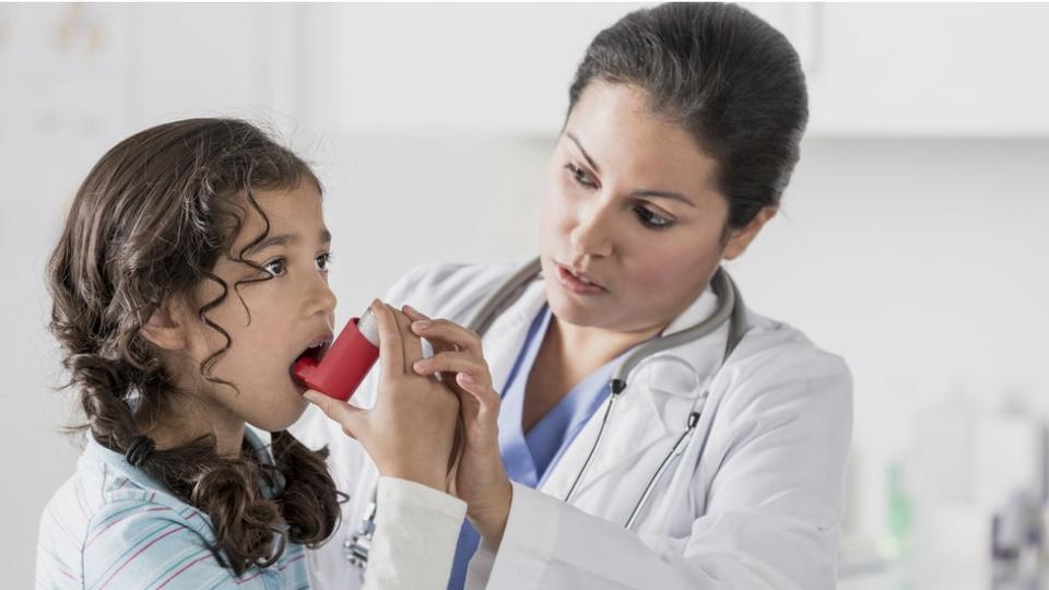 Niña aprendiendo a usar un inhalador.