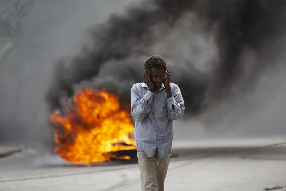 A man walks past a burning barricade during a protest over the death of journalist Romelo Vilsaint, in Port-au-Prince, Haiti, Sunday, Oct. 30, 2022. Vilsaint died Sunday after being shot in the head when police opened fire on reporters demanding the release of one of their colleagues who was detained while covering a protest, witnesses told The Associated Press. (AP Photo/Odelyn Joseph)