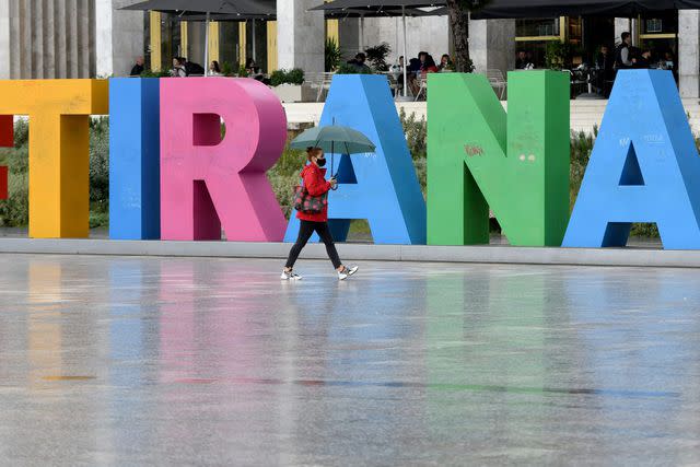 GENT SHKULLAKU/AFP via Getty Images A woman wearing a face mask, walks in Tirana&#39;s main square.