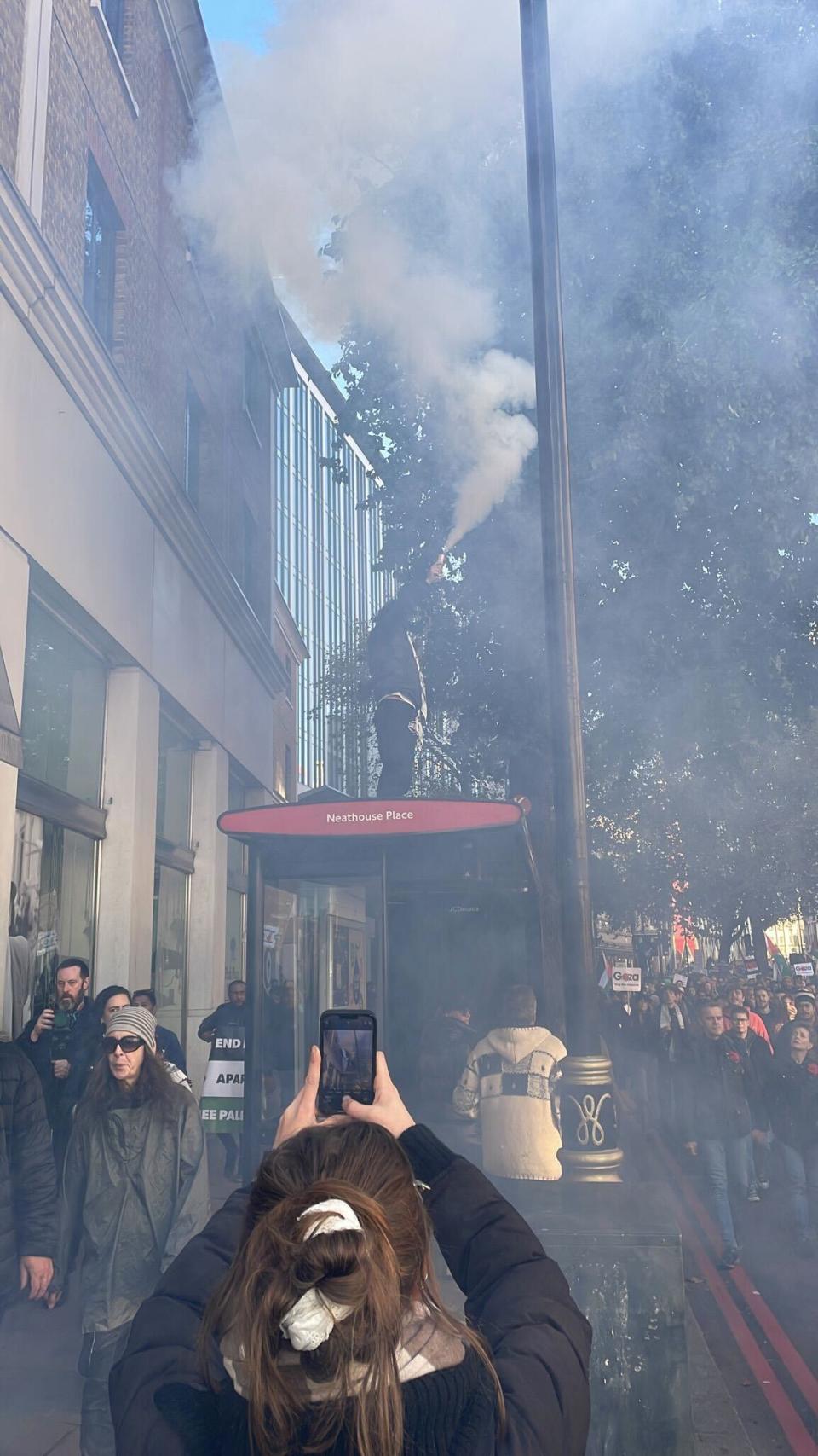 A swarm of people surround the red flare as they call for a ceasefire (Provided)