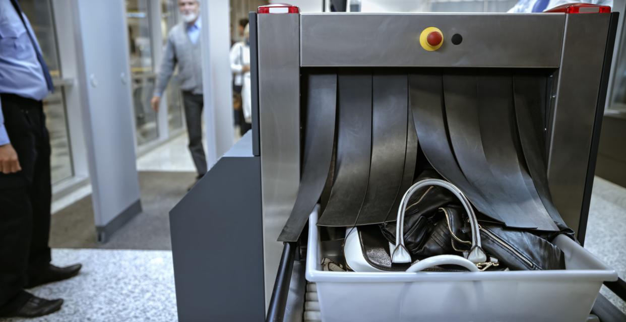 Checking baggage on conveyor belt at airport.