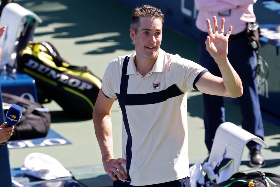 John Isner waves to the crowd during an on-court interview after his match against Michael Mmoh.