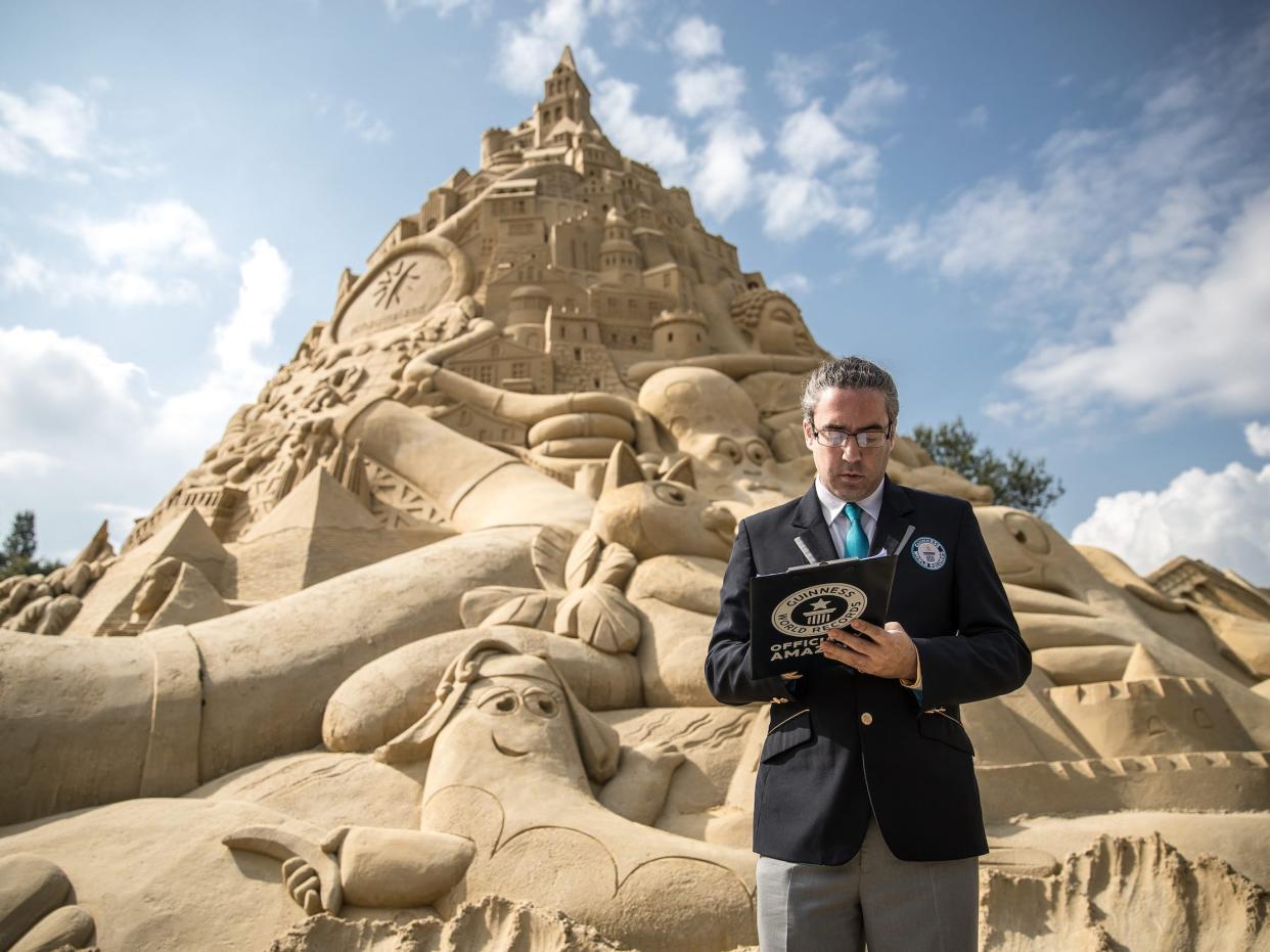A representative from the Guinness Book of World Records looks at his notes next to a massive sandcastle in 2017 in Germany.