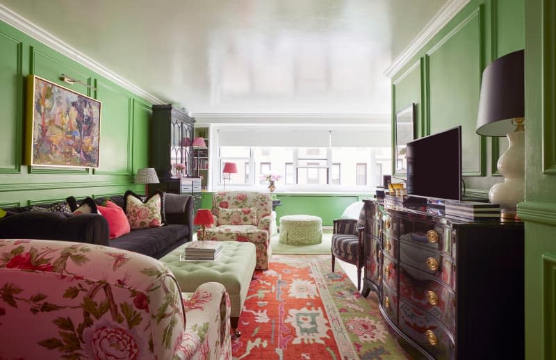 TV atop dresser in front of seating area of green living room.