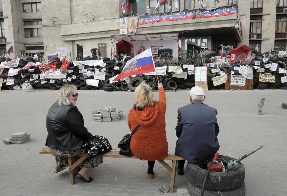 Pro-Russian activists with Russian flag sitting at a barricade at the regional administration building in Donetsk, Ukraine, Wednesday, April 23, 2014. Pro-Russian gunmen in eastern Ukraine said on Wednesday that they are holding captive American journalist with Vice News Simon Ostrovsky who has not been seen since early Tuesday April 22. Ostrovsky has been covering the crisis in Ukraine for some weeks and was reporting about groups of masked gunmen seizing government buildings in eastern Ukrainian. (AP Photo/Efrem Lukatsky)