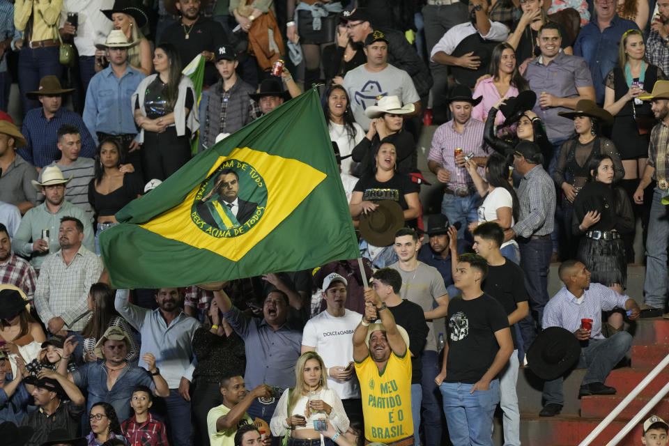 A man waves a Brazilian flag with the image of Brazilian President Jair Bolsonaro, who is running for a second term, during the the Barretos Rodeo International Festival in Barretos, Sao Paulo state Brazil, Friday, Aug. 26, 2022. Brazil's general elections are scheduled for Oct. 2, 2022. (AP Photo/Andre Penner)