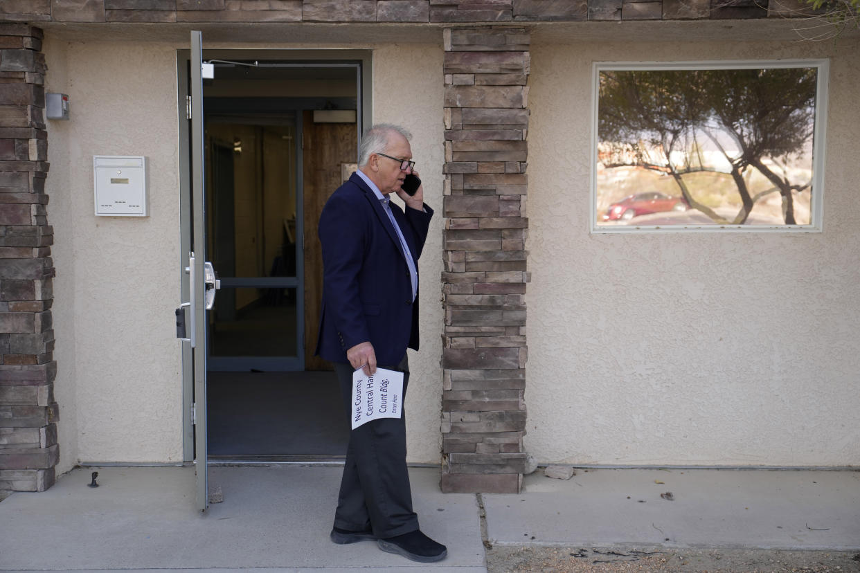Interim Nye County Clerk Mark Kampf speaks on the phone outside of a building where early votes are being counted Wednesday, Oct. 26, 2022, in Pahrump, Nev. Ballot counting began in the county where officials citing concerns about voting machine conspiracy theories pressed forward with an unprecedented hand tally of votes cast by mail in advance of Election Day. (AP Photo/John Locher)