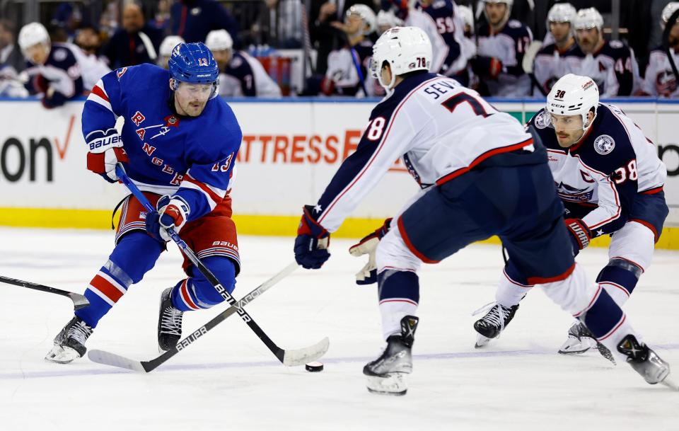 New York Rangers left wing Alexis Lafreniere (13) plays the puck against Columbus Blue Jackets defenseman Damon Severson (78) and center Boone Jenner (38) during the second period of an NHL hockey game, Sunday, Nov. 12, 2023, in New York. (AP Photo/Noah K. Murray)