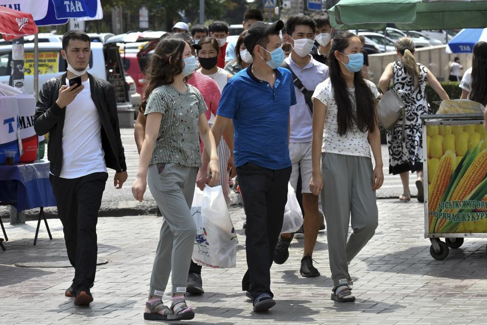 Youths in face masks walk through a street market in Bishkek, Kyrgyzstan, Friday, July 24, 2020. Coronavirus cases surged in Kyrgyzstan after authorities lifted a tight lockdown in May, overwhelming the health care system. But now thousands of volunteers are helping medical workers in busy hospitals, using cars into makeshift ambulances and finding protective gear, drugs, supplies and equipment. (AP Photo/Vladimir Voronin)