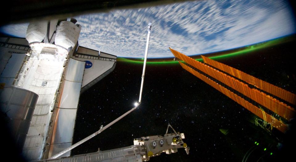 This panoramic view, photographed from the International Space Station, looking past the docked space shuttle Atlantis' cargo bay and part of the station including a solar array panel toward Earth, was taken on July 14 as the joint complex passed over the southern hemisphere. Aurora Australis or the Soutern Lights can be seen on Earth's horizon and a number of stars are visible also.