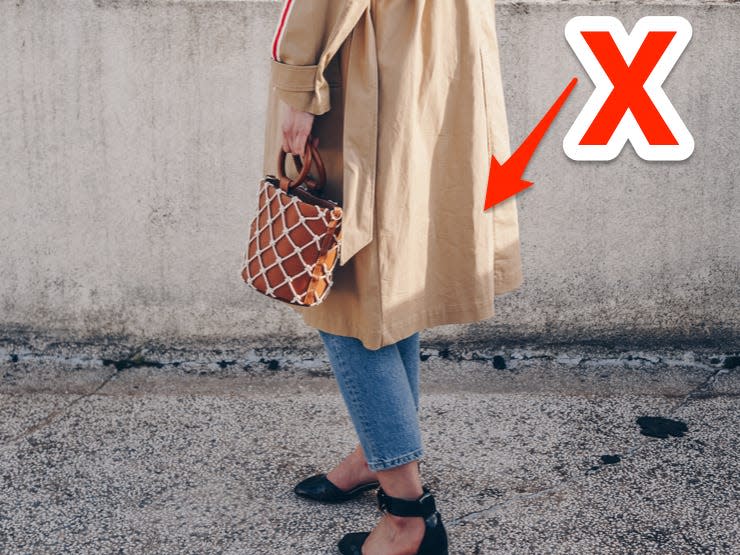 red x and arrow pointing at a 3/4 hem of a trench coat someone is wearing over jeans