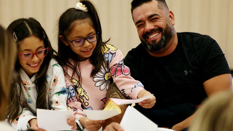 Elizabeth and Aileen Reyes laugh with their dad Carlos as they learn about what it’s like for refugees at “A day in the life of a refugee” event in Lehi on Friday.