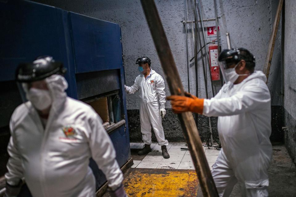 Varios empleados del crematorio trabajan en la cremación de un cuerpo. (Photo by PEDRO PARDO/AFP via Getty Images)