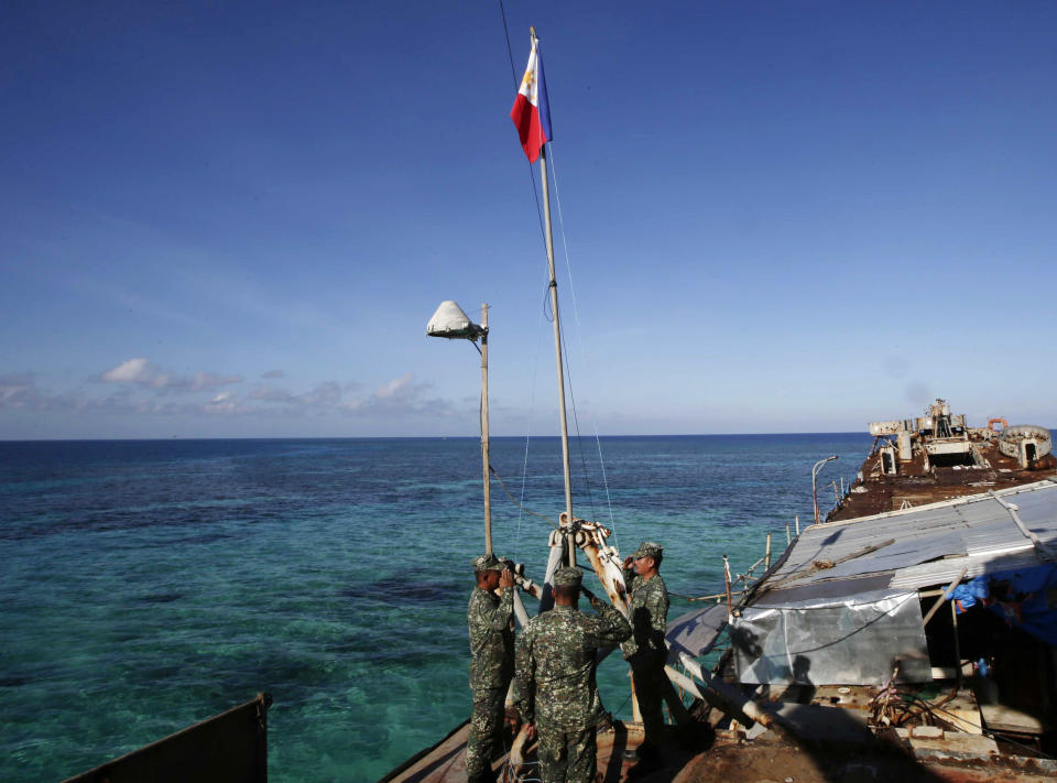 Philippine Marines raise the Philippine flag on the first day of their deployment on the dilapidated navy ship LT57 BRP Sierra Madre at the disputed Second Thomas Shoal, locally known as Ayungin Shoal, Sunday, March 30, 2014, off the South China Sea. On Saturday, China Coast Guard attempted to block the Philippine government vessel AM700 carrying fresh troops and supplies, but the latter successfully managed to dock beside the ship to replace troops who were deployed for five months. (AP Photo/Bullit Marquez)