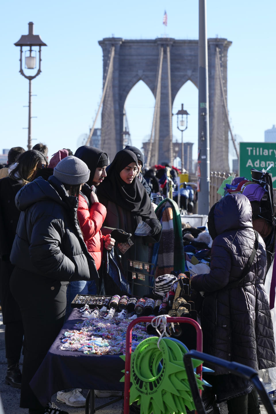 Pedestrians shop at vendors selling souvenirs on the Brooklyn Bridge in New York, Tuesday, Jan. 2, 2024. New York City will ban vendors from the Brooklyn Bridge starting Wednesday, Jan. 3, 2024. The move is intended to ease overcrowding on the famed East River crossing, where dozens of souvenir sellers currently compete for space with tourists and city commuters. (AP Photo/Seth Wenig)