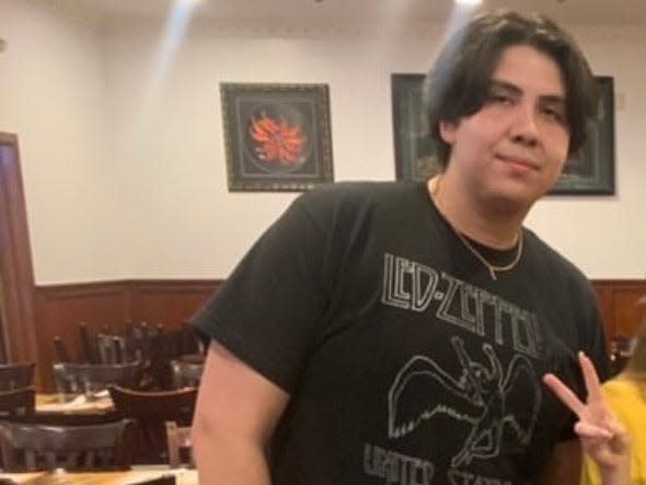 Benji Xavier when he weighed more wearing a black t-shirt and shorts, standing in a restaurant.