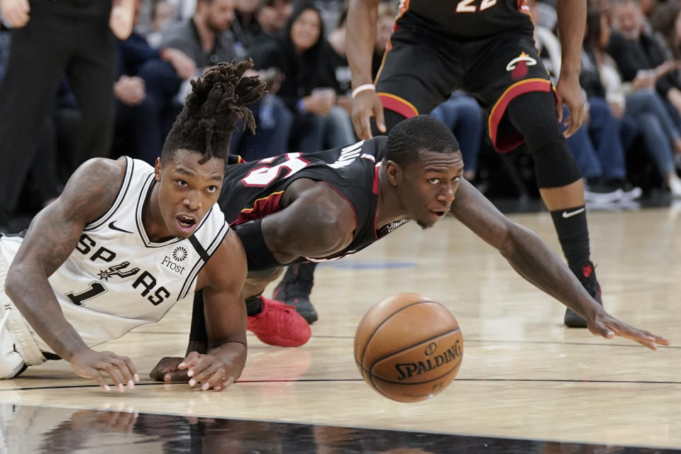 San Antonio Spurs' Lonnie Walker IV (1) and Miami Heat's Kendrick Nunn fall as they chase the ball during the first half of an NBA basketball game, Sunday, Jan. 19, 2020, in San Antonio. (AP Photo/Darren Abate)
