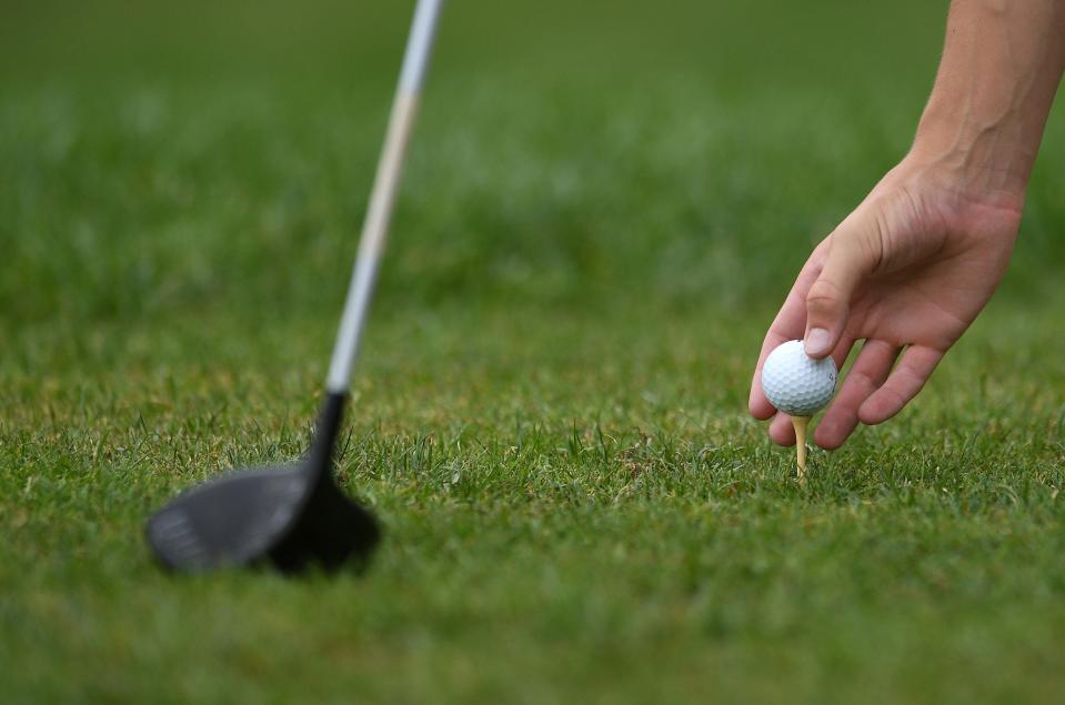 A golfer tees his golf ball on the tee.