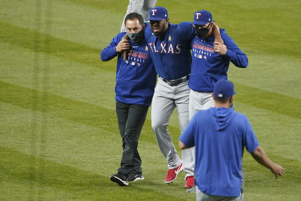 Texas Rangers relief pitcher Joely Rodriguez, second from left, is helped off the field after an injury during the seventh inning of the team's baseball game against the Seattle Mariners, Saturday, Sept. 5, 2020, in Seattle. (AP Photo/Ted S. Warren)