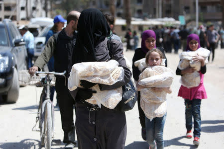 People hold stacks of bread at the city of Douma, Damascus, Syria April 16, 2018. REUTERS/Ali Hashisho