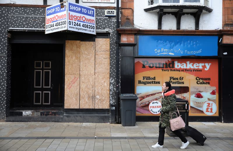 A woman walks past a closed shop in the town centre of Wrexham, Britain