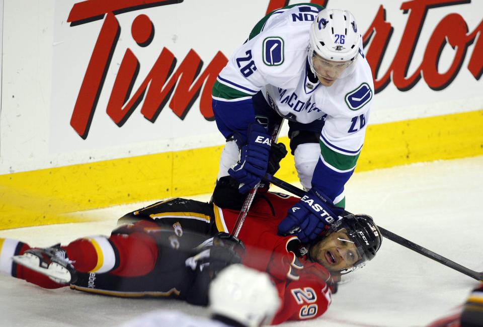 FILE - Vancouver Canucks' Samuel Pahlsson, top, of Sweden, holds down Calgary Flames' Akim Aliu, of Nigeria, during the third period of an NHL hockey game in Calgary, Alberta, Thursday, April 5, 2012. After years of feeling alienated by the NHL and campaigning to diversify the sport, Akim Aliu is getting one more shot at playing pro hockey, this time with the San Jose Sharks minor-league affiliate. Sharks general manager Mike Grier informed reporters at the league’s GM meetings in Florida on Wednesday, March 20, 2024, that he offered Aliu a tryout contract with the American Hockey League San Jose Barracuda for the remainder of the season.(AP Photo/The Canadian Press, Jeff McIntosh, File)