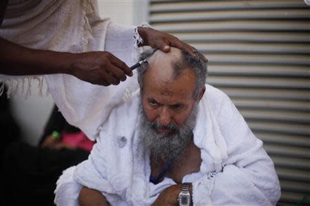 A Muslim pilgrim has his head shaved after casting pebbles at a pillar that symbolizes Satan during the annual haj pilgrimage, on the first day of Eid al-Adha in Mina, near the holy city of Mecca October 15, 2013. REUTERS/Ibraheem Abu Mustafa