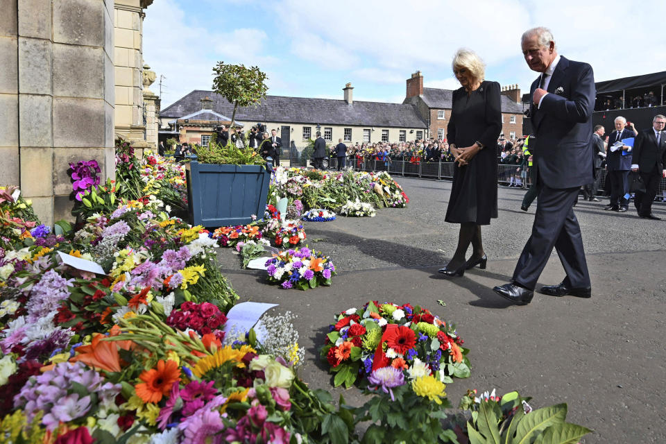 Britain's King Charles III, right, and Camilla, the Queen Consort look at floral tributes as they arrive at Hillsborough Castle, in Belfast, Northern Ireland, Sept. 13, 2022. As King Charles III arrived in Northern Ireland for the first visit since his mother’s death elevated him to the throne, the voices of Belfast offered a sharp reminder of the country’s complicated bloody political realities. (Michael Cooper/PA via AP)